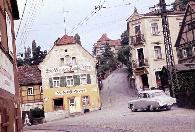 Ulice v Drážďanech-Altwachwitz s historickými budovami a automobilem značky Wartburg, zachycující každodenní život v NDR kolem roku 1960.