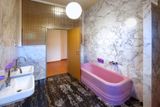 Koupelny jsou z luxusních materiálů, prosvětluje je luxferová stěna a fialové doplňky.