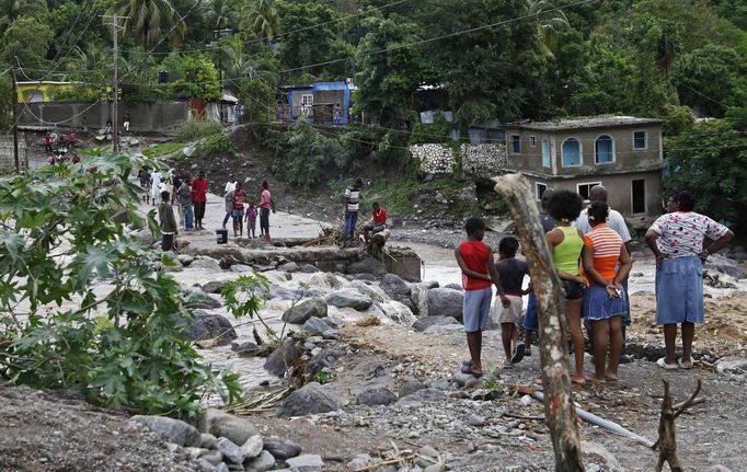 Residents of Kingston try to cross the Hope River after a bridge was washed out by Hurricane Sandy, October 25, 2012. Strengthening rapidly after tearing into Jamaica and crossing the warm Caribbean Sea, Sandy hit southeastern Cuba early on Thursday with 105-mph winds that cut power and blew over trees, with at least three fatalities in Jamaica and Haiti. REUTERS/Gilbert Bellamy (JAMAICA - Tags: ENVIRONMENT DISASTER) Published: Říj. 25, 2012, 5:52 odp.