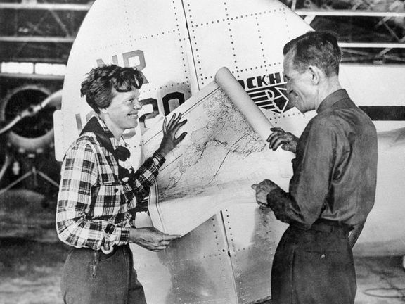 Na nedatovaném snímku pózují letkyně Amelia Earhartová (vlevo) a navigátor Fred Noonan s mapou Tichého oceánu, na níž je vyznačena trasa jejich letu kolem světa.