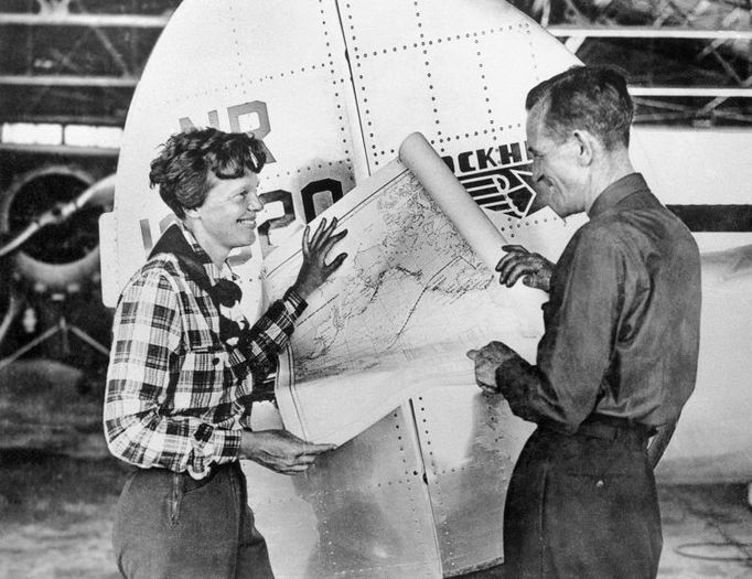 Na nedatovaném snímku pózují letkyně Amelia Earhartová (vlevo) a navigátor Fred Noonan s mapou Tichého oceánu, na níž je vyznačena trasa jejich letu kolem světa.