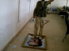 Bojovník Svobodné syrské armády stojí na fotografii bývalého prezidenta Háfize Asada, Bašárova otce, na dobytém hraničním přechodu do Turecka.