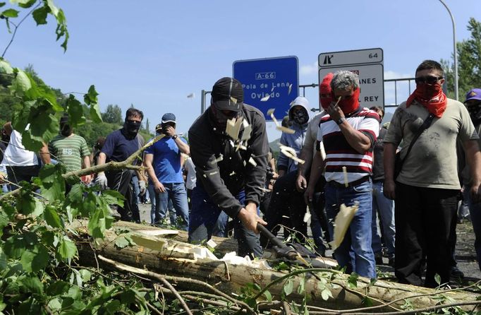 A coal miner cuts a tree trunk to make a barricade on the motorway A-66 to protest against government spending cuts in the mining sector in Campomanes, near Oviedo, northern Spain, May 30, 2012. REUTERS/Eloy Alonso (SPAIN - Tags: CIVIL UNREST BUSINESS EMPLOYMENT) Published: Kvě. 30, 2012, 3:23 odp.