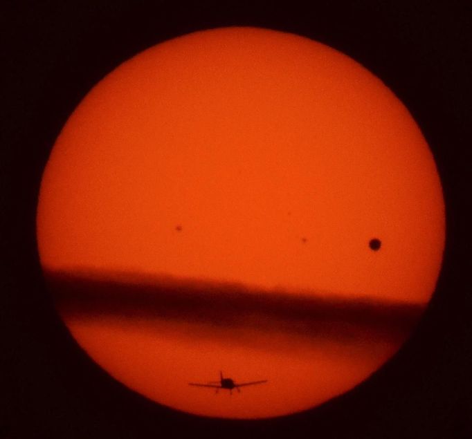 A plane flies under a thin layer cloud crossing the sun as Venus (R) moves past the sun are seen through a coelostat at the Griffith Observatory in Los Angeles, June 5, 2012. The planet Venus made a slow transit across the face of the sun on Tuesday, the last such passing that will be visible from Earth for 105 years. REUTERS/Gene Blevins (UNITED STATES - Tags: TRANSPORT ENVIRONMENT SCIENCE TECHNOLOGY TPX IMAGES OF THE DAY) Published: Čer. 6, 2012, 6:14 dop.