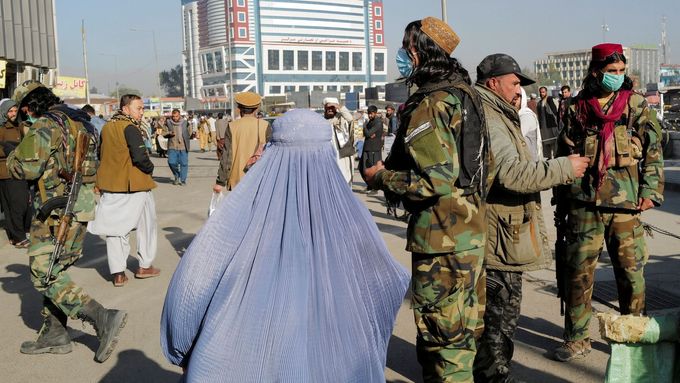 Člen Tálibánu vedle ženy jdoucí v burce, Kábul.
