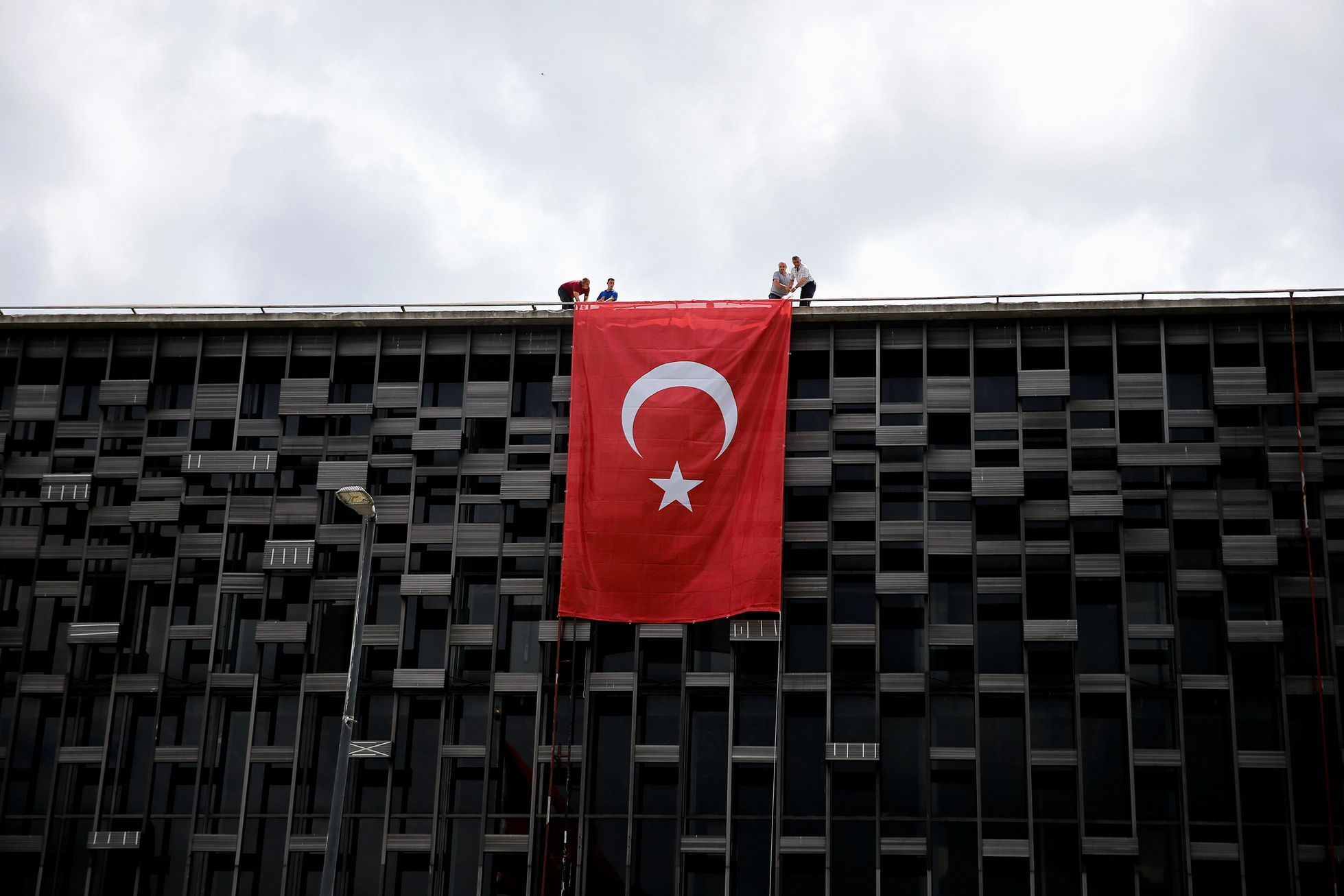 Lidé vyvěšují tureckou vlajku na budovu na Taksimském náměstí v Istanbulu