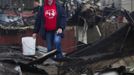 A woman stands outside the wreckage of homes devastated by fire and the effects of Hurricane Sandy in the Breezy Point section of the Queens borough of New York October 31, 2012. The U.S. Northeast began an arduous slog back to normal on Wednesday after historic monster storm Sandy crippled transportation, knocked out power for millions and killed at least 64 people with a massive storm surge that caused epic flooding. REUTERS/Shannon Stapleton (UNITED STATES - Tags: ENVIRONMENT DISASTER) Published: Říj. 31, 2012, 8:38 odp.