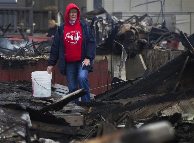 A woman stands outside the wreckage of homes devastated by fire and the effects of Hurricane Sandy in the Breezy Point section of the Queens borough of New York October 31, 2012. The U.S. Northeast began an arduous slog back to normal on Wednesday after historic monster storm Sandy crippled transportation, knocked out power for millions and killed at least 64 people with a massive storm surge that caused epic flooding. REUTERS/Shannon Stapleton (UNITED STATES - Tags: ENVIRONMENT DISASTER) Published: Říj. 31, 2012, 8:38 odp.