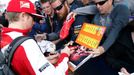 Ferrari Formula One driver Kimi Raikkonen of Finland (L) signs autographs as he arrives for the first practice session of the Australian F1 Grand Prix at the Albert Park