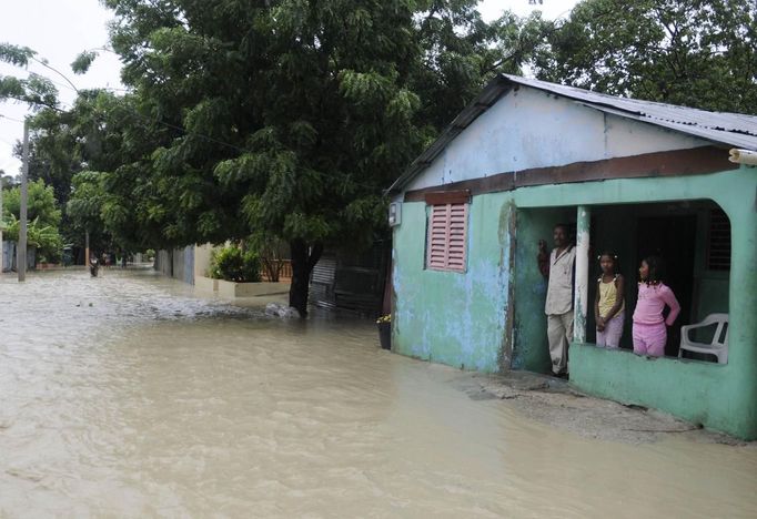 A family looks out from their porch at the floodwater from Tropical Storm Isaac in Vicente Noble, Barahona province, August 25, 2012. Tropical Storm Isaac emerged over warm Caribbean waters on Saturday slightly weaker but ready to regroup after dumping torrential rains on the Dominican Republic and Haiti. REUTERS/Ricardo Rojas (DOMINICAN REPUBLIC - Tags: DISASTER ENVIRONMENT) Published: Srp. 25, 2012, 5 odp.