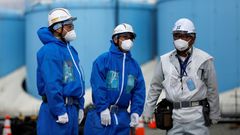 Pracovníci společnosti TEPCO před nádržemi na skladování radioaktivní vody ve Fukušimě