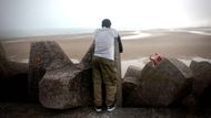 Migrant vyčkává na molu, než se na dohled objeví nafukovací člun, který ho ilegálně převeze přes Lamanšský průliv. Snímek vznikl na francouzském pobřeží u Gravelines poblíž Calais.