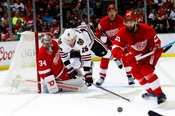 Chicago Blackhawks center Arťom Anisimov (15) trips over Detroit Red Wings goalie Petr Mrázek (34) as Detroit Red Wings defenseman Kyle Quincey (27) goes for the puck