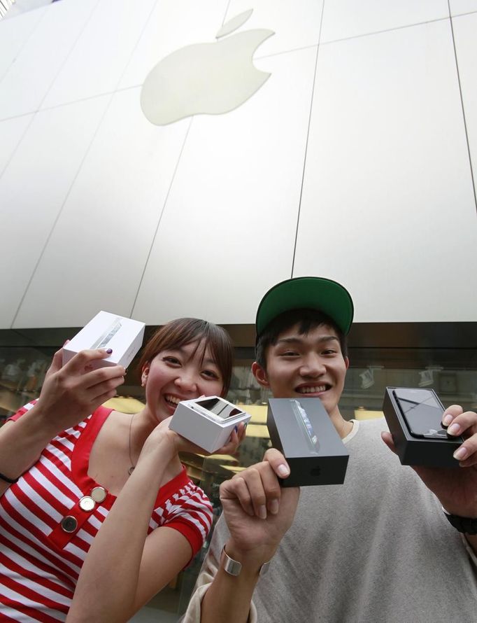 Kae Shibata (L) and Yutaro Noji show off their new Apple Inc's iPhone 5 after waiting for two days outside an Apple Store in Tokyo's Ginza district September 21, 2012. Apple Inc's iPhone 5 hit stores around the globe on Friday, with fans snapping up the device that is expected to fuel a huge holiday quarter for the consumer giant. REUTERS/Yuriko Nakao (JAPAN - Tags: BUSINESS SCIENCE TECHNOLOGY) Published: Zář. 21, 2012, 12:56 dop.