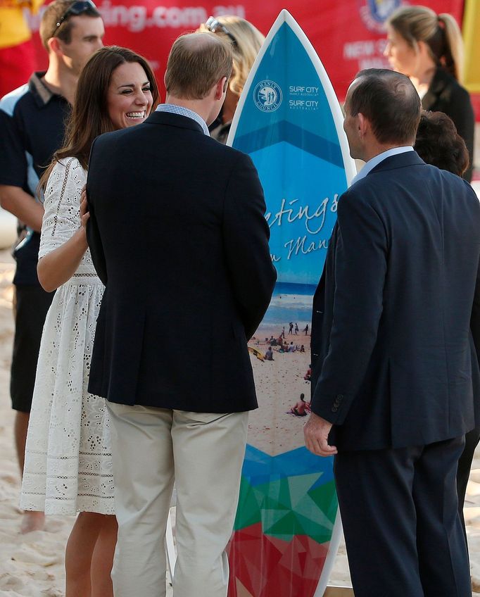 Catherine, Britain's Duchess of Cambridge, laughs with her husband Prince William after being presented with a surf board on Manly beach in Sydney