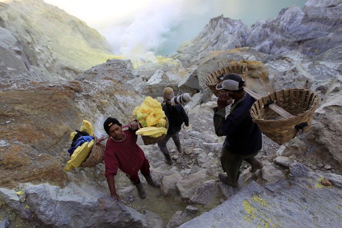 Indonéští horníci těží síru v kráteru Kawah Ijen, Východní Jáva, Indonésie, 24. října 2012. Síru nosí v koších na vzdálenost téměř 3 km.