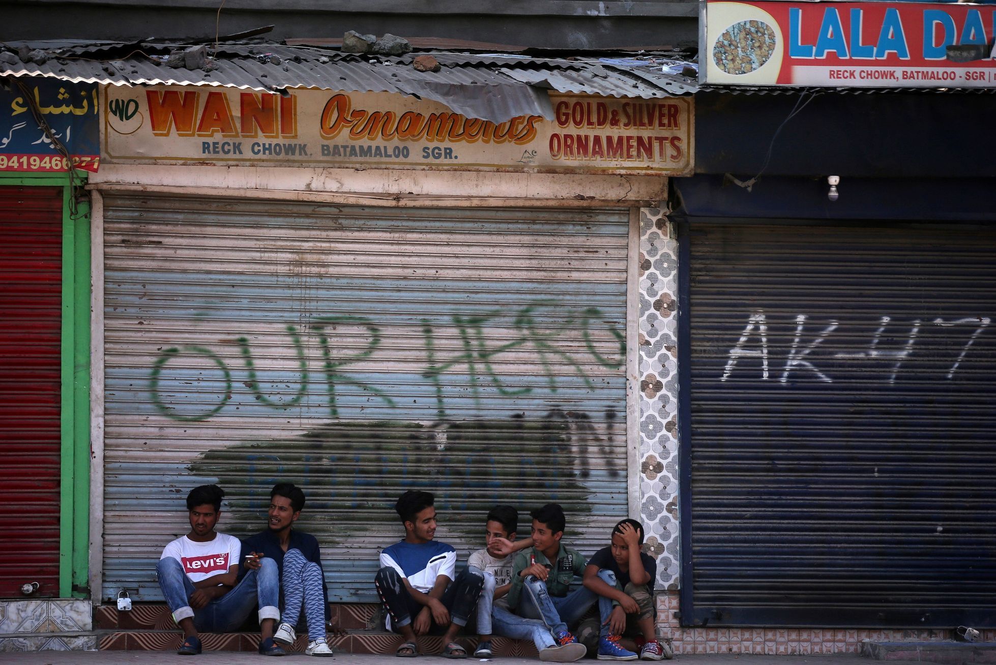 Chlapci v Kašmíru sedí před obchodem zavřeným kvůli indickému zákazu.
