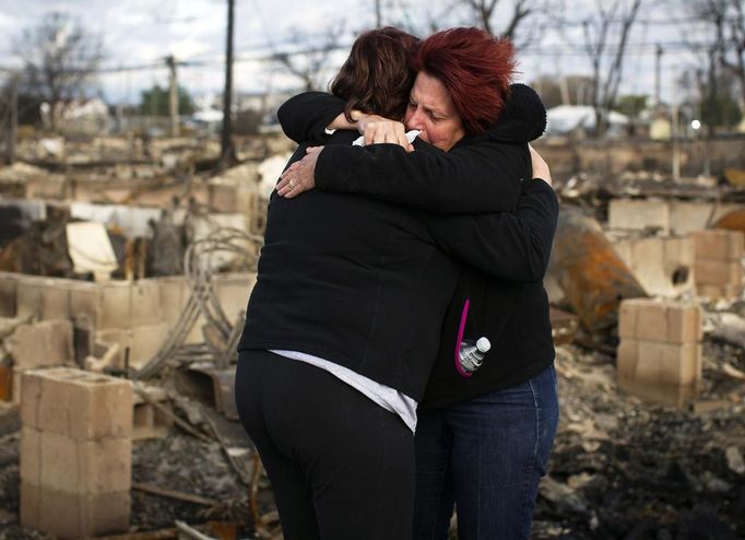 Neighbors Lucille Dwyer (R) and Linda Strong embrace after looking through the wreckage of their homes devastated by fire and the effects of Hurricane Sandy in the Breezy Point section of the Queens borough of New York October 31, 2012. The U.S. Northeast began crawling back to normal on Wednesday after monster storm Sandy crippled transportation, knocked out power for millions and killed at least 45 people in nine states with a massive storm surge and rain that caused epic flooding. REUTERS/Shannon Stapleton (UNITED STATES - Tags: ENVIRONMENT DISASTER) Published: Říj. 31, 2012, 3:48 odp.