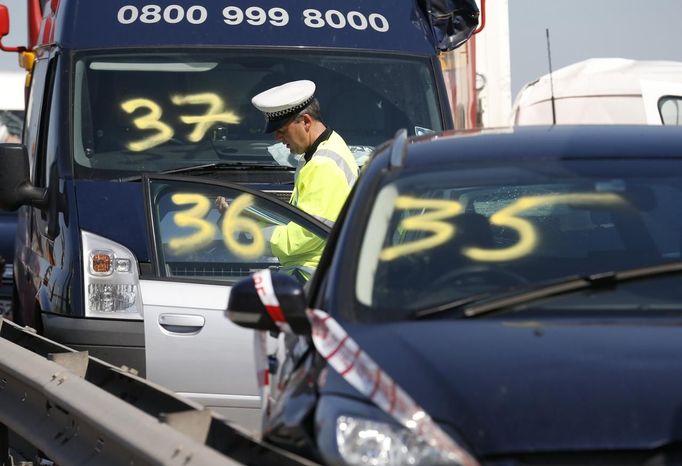 A police officer stands amongst the wreckage of some of the 100 vehicles involved in multiple collisions, which took place in dense fog during the morning rush hour, on the Sheppey Bridge in Kent, east of London, September 5, 2013. Eight people were seriously injured and dozens hurt in the multiple crashes.