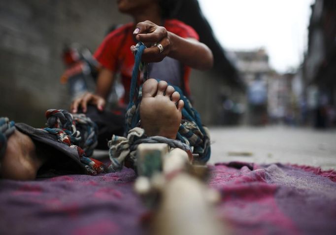 Drumpal Choudhary, 11, a street performer ties his legs with a wooden pole as he gets ready to perform a trick at a street in Kathmandu August 15, 2012. Drumpal, his brother, Gchan and sister, Shivani, came to Kathmandu from India 5 years ago. They earn their living by performing tricks on the streets of Kathmandu. According to Drumpal, they earn around $10 a day by performing tricks, which is not enough to feed their 10-member family living together in a small hut without a proper toilet or any basic needs. REUTERS/Navesh Chitrakar (NEPAL - Tags: SOCIETY POVERTY IMMIGRATION) Published: Srp. 15, 2012, 4:47 odp.