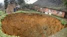 Huge 20m wide sinkhole appears in yard in front of family house, Leshan, Sichuan Province, China - 12 Jan 2011 2011-01-12 00:00:00 Mandatory Credit: Photo by Quirky China News / Rex Features ( 1271190a ) The 20-meter wide (66 ft) sinkhole that has appeared in front of Zhang Fengrong's home Huge 20m wide sinkhole appears in yard in front of family house, Leshan, Sichuan Province, China - 12 Jan 2011 A huge 20-meter wide (66 ft) sinkhole formed overnight in the yard of a family home in Leshan, southwest China's Sichuan Province. According to 58-year-old Zhang Fengrong, at 2am on the day in question he heard a loud roaring sound coming from outside. When he went to investigate he was stunned to discover a huge pit, the depth of which is unknown, opening up before his eyes. Fengrong said he and several relatives had tried to measure the depth of the pit using a rope attached to a heavy iron, but after they used up the 40-meter long rope the iron still hadn't hit ground. "It used to be land for vegetables, but in a blink the land disappeared along with several fruit trees," said Fengrong's son Zhang Shiyin. Shiyin said when the sinkhole appeared he rushed outside when he heard his parents cries. At that point, he sais, the chasm was only 3 meters in diameter but it soon quickly enlarged with the hole stopping less than a meter from the house.