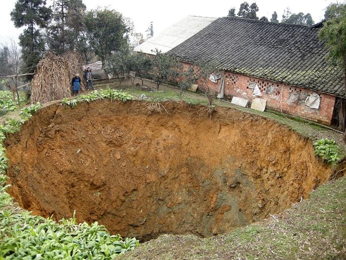 Huge 20m wide sinkhole appears in yard in front of family house, Leshan, Sichuan Province, China - 12 Jan 2011 2011-01-12 00:00:00 Mandatory Credit: Photo by Quirky China News / Rex Features ( 1271190a ) The 20-meter wide (66 ft) sinkhole that has appeared in front of Zhang Fengrong's home Huge 20m wide sinkhole appears in yard in front of family house, Leshan, Sichuan Province, China - 12 Jan 2011 A huge 20-meter wide (66 ft) sinkhole formed overnight in the yard of a family home in Leshan, southwest China's Sichuan Province. According to 58-year-old Zhang Fengrong, at 2am on the day in question he heard a loud roaring sound coming from outside. When he went to investigate he was stunned to discover a huge pit, the depth of which is unknown, opening up before his eyes. Fengrong said he and several relatives had tried to measure the depth of the pit using a rope attached to a heavy iron, but after they used up the 40-meter long rope the iron still hadn't hit ground. "It used to be land for vegetables, but in a blink the land disappeared along with several fruit trees," said Fengrong's son Zhang Shiyin. Shiyin said when the sinkhole appeared he rushed outside when he heard his parents cries. At that point, he sais, the chasm was only 3 meters in diameter but it soon quickly enlarged with the hole stopping less than a meter from the house.