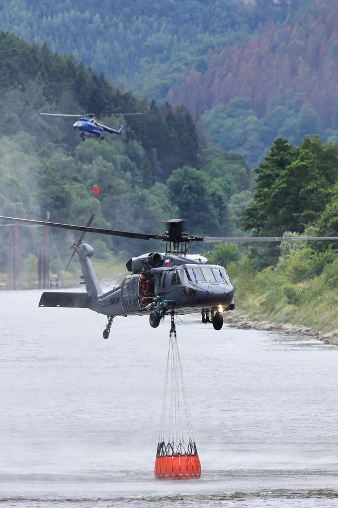 Vrtulník Sikorsky UH-60 Black Hawk (v popředí) polské policie během hašení požáru v Národním parku České Švýcarsko. 27. 7. 2022
