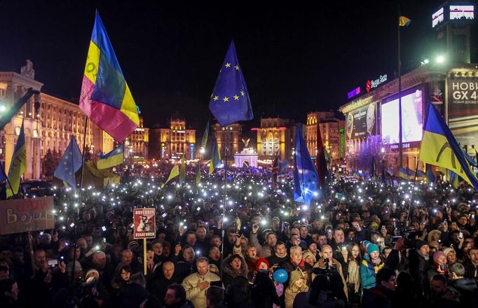 Demonstranti podporující vstup Ukrajiny do EU svítí na náměstí v Kyjevě mobily nad hlavou.