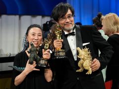 Kyoko Shibuya and Takashi Yamazaki pose with the Oscars for Godzilla Minus One.