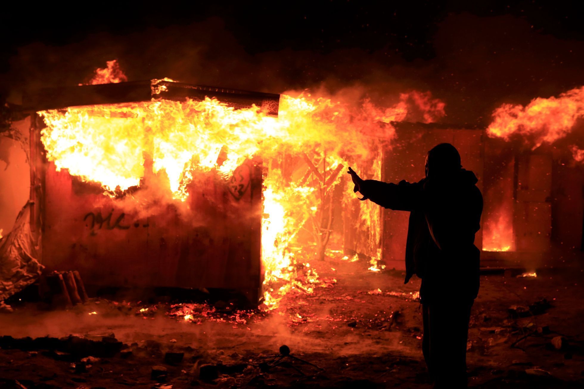 Migranti zapalují přístřešky při protestech proti vyklízení tábora u Calais
