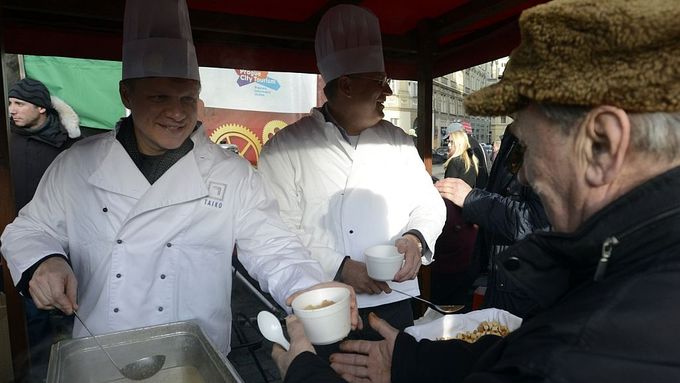 Pražský primátor Tomáš Hudeček (vlevo) servíruje na Staroměstském náměstí v Praze štědrovečerní rybí polévku.
