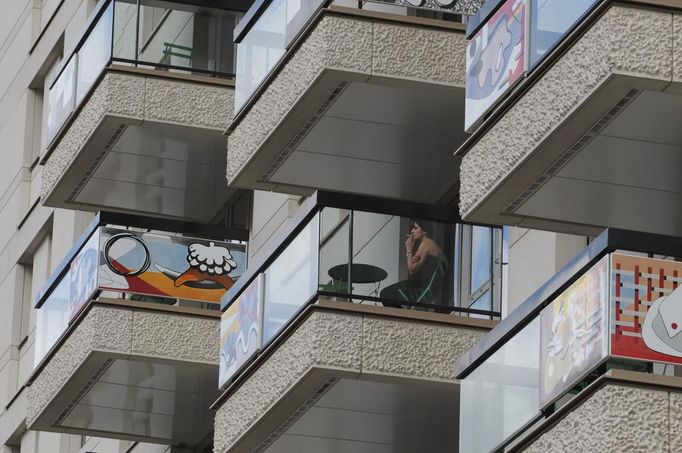 A visitor testing facilities overnight smokes a cigarette on one of the brightly decorated balconies in the Olympic Village built for the London 2012 Olympic Games in Stratford, east London on June 29, 2012. The village will accomodate up to 16,000 athletes and officials from more than 200 nations. Picture taken June 29, 2012. REUTERS/Olivia Harris (BRITAIN - Tags: BUSINESS CONSTRUCTION SPORT CITYSPACE) Published: Čer. 30, 2012, 12:04 odp.