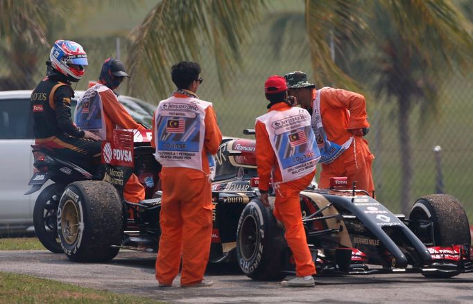 Lotus Formula One driver Romain Grosjean of France is driven back to pits after leaving his car during the second practice session of the Malaysian F1 Grand Prix at Sepan