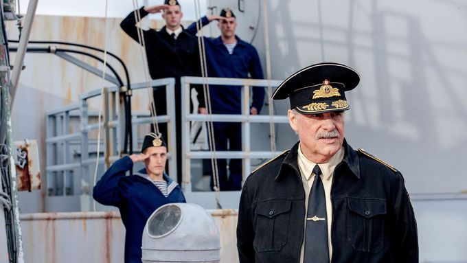 Peter Simonischek přehlíží loďstvo z kapitánského můstku podoben parodii na důstojného kníratého ruského admirála.
