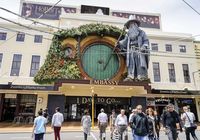 Pedestrians walk past a giant model of the J. R. R. Tolkien character Gandalf mounted on the front of The Embassy Theatre in Wellington November 27, 2012, where the world premier of The Hobbit film will screen on Wednesday. New Zealand's capital city was rushing to complete its transformation into a haven for hairy feet and pointed ears on Tuesday as stars jetted in for the long-awaited world premiere of the first movie of the Hobbit trilogy. REUTERS/Mark Coote (NEW ZEALAND - Tags: ENTERTAINMENT) Published: Lis. 27, 2012, 3:20 dop.