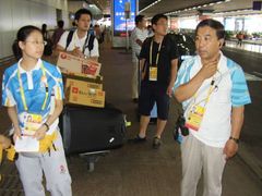 Olympijští dobrovolníci organizují před letištěm dopravu do olympijské vesničky a hotelů. Trvá jim to dlouho, ale zařídí ji.