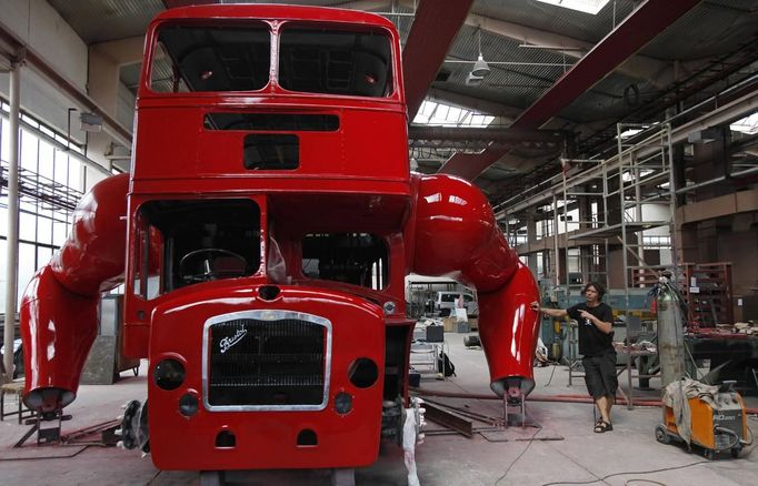 Artist David Cerny gestures at a factory hall in Prague as he works on his project to transform a London bus into a robotic sculpture June 25, 2012. The bus, which Cerny hopes could become an unofficial mascot of the London 2012 Olympic Games, does push-ups with the help of an engine powering a pair of robotic arms and the motion is accompanied by a recording of sounds evoking tough physical effort. It will be parked outside the Czech Olympic headquarters in London for the duration of the Games. Picture taken June 25, 2012. REUTERS/David W Cerny (CZECH REPUBLIC - Tags: SOCIETY SPORT OLYMPICS TRANSPORT) Published: Čec. 22, 2012, 5:57 odp.