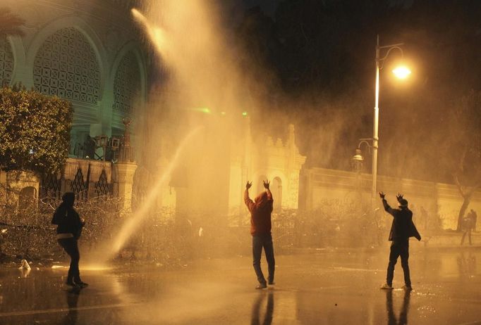 Protesters opposing Egyptian President Mohamed Mursi and the Muslim Brotherhood chant anti-government slogans while police spray water on them from inside the Presidential Palace, as some of the protesters try to break through one of the gates of the palace, in Cairo February 11, 2013. Protesters demanding the departure of Mursi clashed with police outside his palace on Monday on the second anniversary of the overthrow of veteran autocrat Hosni Mubarak. Dozens of youths threw rocks at the Ettihadiya palace after a peaceful march by thousands of demonstrators who accused Mursi's conservative Muslim Brotherhood of hijacking Egypt's democratic revolution and seeking to monopolise power. REUTERS/Asmaa Waguih (EGYPT - Tags: POLITICS CIVIL UNREST) Published: Úno. 11, 2013, 7:27 odp.