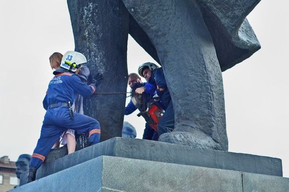 Záchranáři v Novosibirsku odřezávají demonstrantku, připoutanou k soše Lenina. 