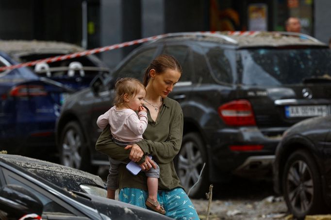 Žena prochází kolem obytného domu, který zničila ruská raketa.