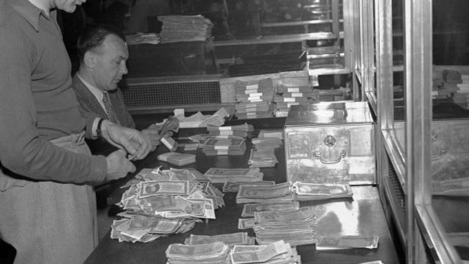 Dne 30. května 1953 schválilo NS zákon o peněžní reformě. Čs. občané přicházejí do výměnných středisek, aby si vyměnili staré peníze za novou měnu. Na sn. bankovní úředníci přepočítávají staré peníze
