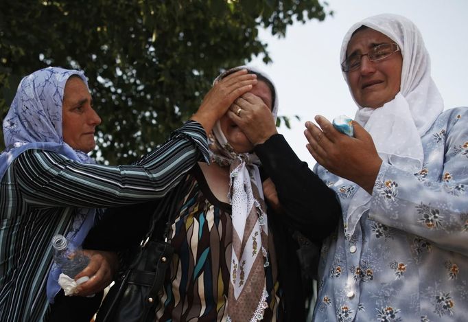 Bosnian women cry as trucks carrying 520 coffins of newly identified victims of the 1995 Srebrenica massacre leave Visoko morgue July 9, 2012. The bodies of the recently identified victims will be transported to the memorial centre in Potocari where they will be buried on July 11 marking the 17th anniversary of the massacre in which Bosnian Serb forces commanded by Ratko Mladic killed up to 8,000 Muslim men and boys and buried them in mass graves. REUTERS/Dado Ruvic (BOSNIA AND HERZEGOVINA - Tags: CIVIL UNREST POLITICS ANNIVERSARY) Published: Čec. 9, 2012, 11:11 dop.