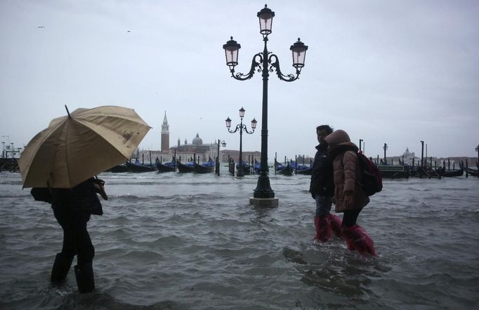 People walk through a flooded street during a period of seasonal high water in Venice November 11, 2012. The water level in the canal city rose to 149 cm (59 inches) above normal, according to local monitoring institute Center Weather Warnings and Tides. REUTERS/Manuel Silvestri (ITALY - Tags: ENVIRONMENT SOCIETY) Published: Lis. 11, 2012, 2:23 odp.