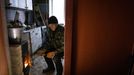 Volodymyr Tkachenko, 78, fires up a wood stove in the kitchen of his apartment that lacks central heating, water and gas in the frontline town of Lyman, amid Russia’s att