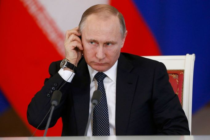 Russian President Vladimir Putin adjusts his headphones during a joint news conference following a meeting with Iranian President Hassan Rouhani at the Kremlin.