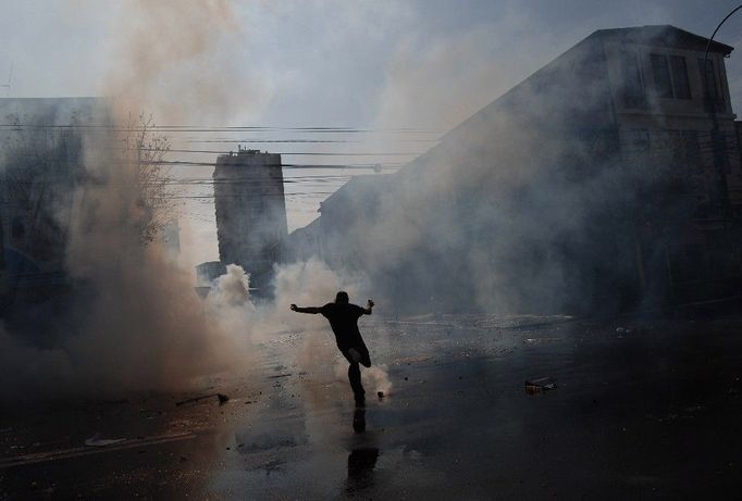 Demonstrant nakopává lahev se slzným plynem během protivládních protestů v chilském Valparaisu.