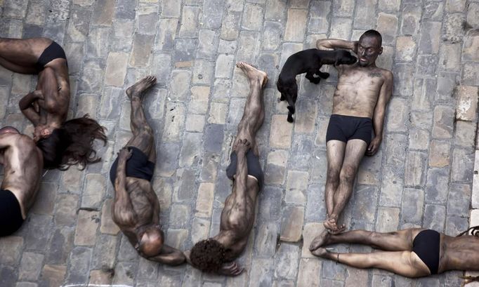 Animal rights protesters lie covered in black paint as they form the words "Stop bullfighting" during a demonstration calling for the abolition of bull runs and bullfights, a day before the start of the famous running of the bulls San Fermin festival in Pamplona July 5, 2012. The annual week-long fiesta gets underway July 6, with the first bull run in the morning of July 7. REUTERS/Susana Vera (SPAIN - Tags: CIVIL UNREST SOCIETY POLITICS) Published: Čec. 5, 2012, 12:19 odp.