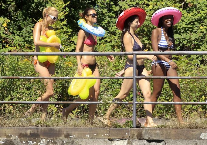 Women wearing bikinis walk along the Limmat river during hot sunny summer weather in Zurich August 18, 2012. The Federal Office of Meteorology MeteoSwiss has launched a warning for a heat wave for the weekend until Wednesday August 22. REUTERS/Arnd Wiegmann (SWITZERLAND - Tags: ENVIRONMENT SOCIETY) Published: Srp. 18, 2012, 2:29 odp.