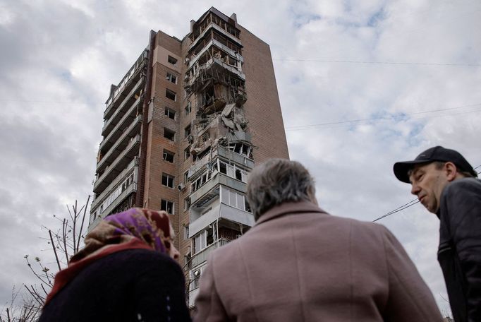 Místní se dívají na zničený obytný dům po útoku dronu na Charkov.