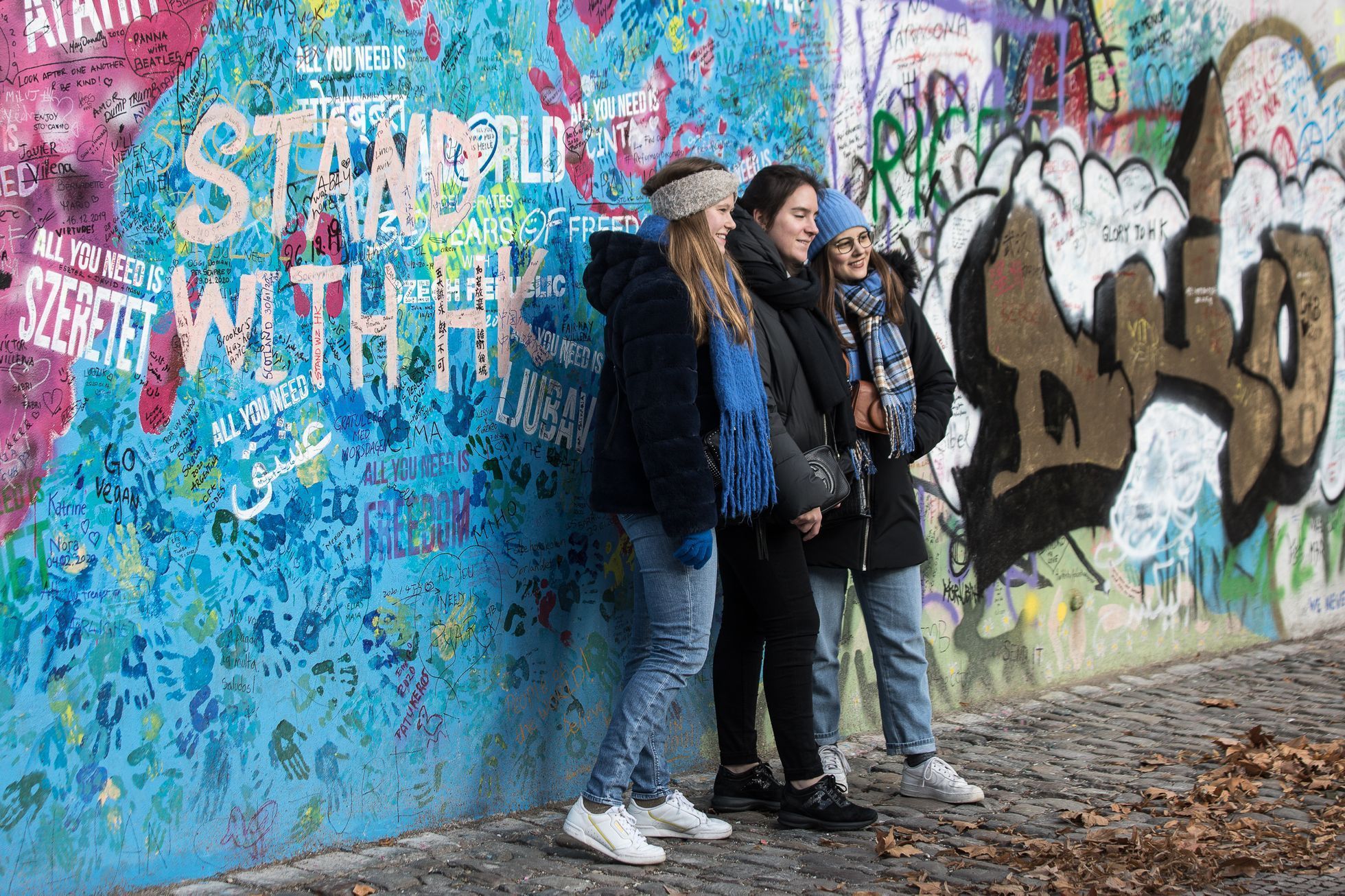 Lennonova zeď po třech měsících od malování - turisté, graffiti